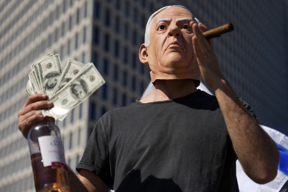 An Israeli demonstrator wears a mask depicting Israeli Prime Minister Benjamin Netanyahu during a protest against plans by his government to overhaul the judicial system, in Tel Aviv, Israel, Thursday ...