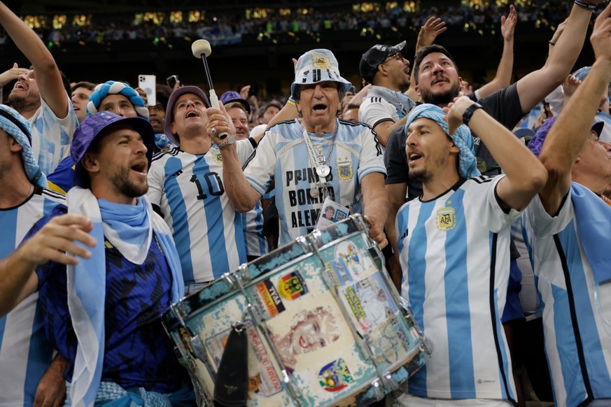Carlos Pascual, otherwise known as El Tula, an 82 year-old Argentinian drummer, at his thirteenth World Cup, is flanked by his sons as he bashes his drum given to him by Juan Peron, and featuring imag ...