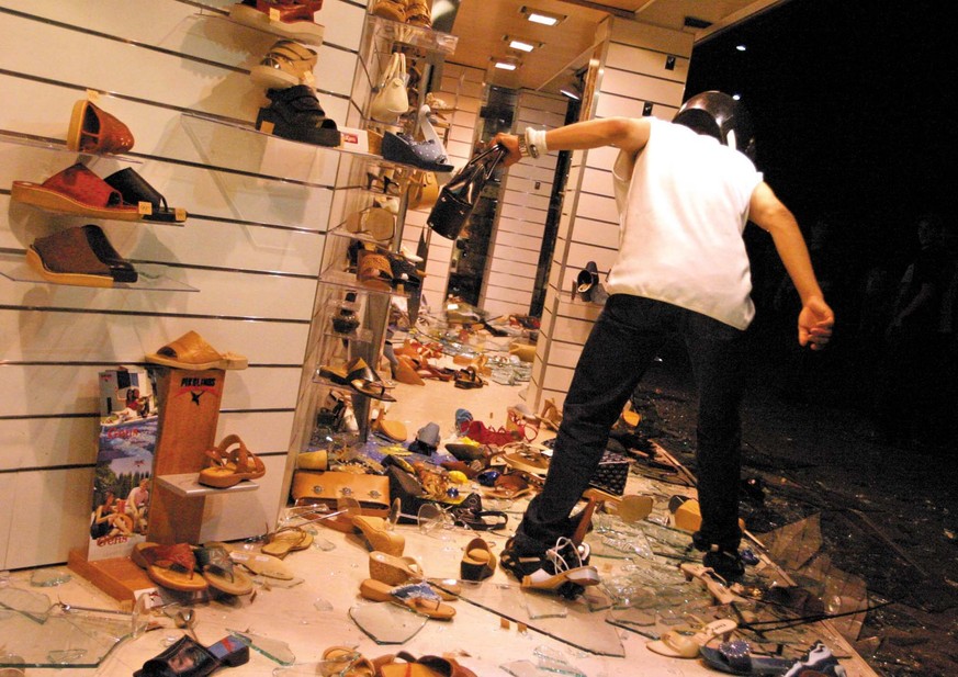 A masked protester is looting a hand bag from the Aeschbach shoes store window shop in downton Geneve, late Sunday night 01 June 2003. Hundreds of anti globalism protesters clashed last night with Swi ...