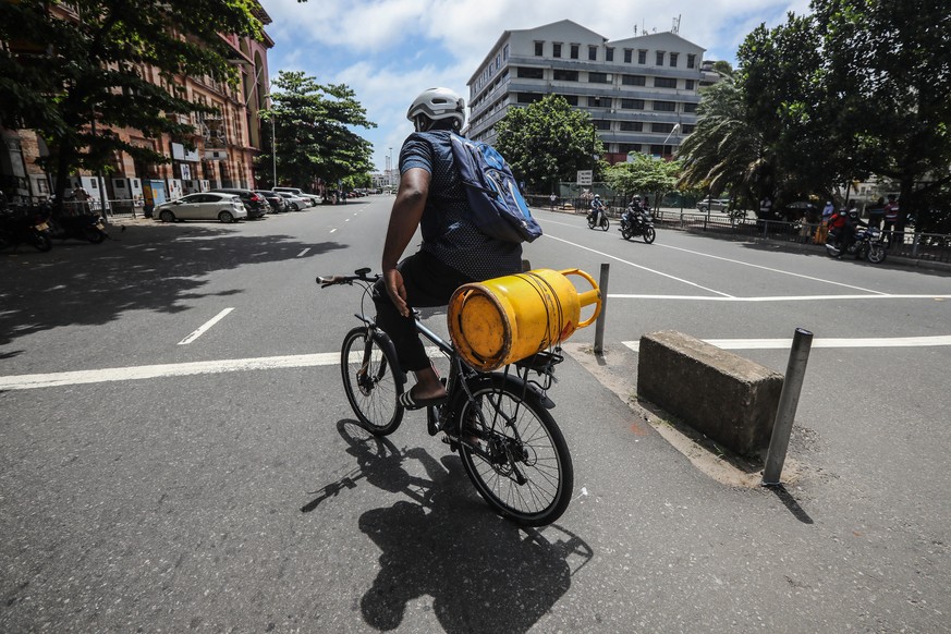 epa10040966 A Sri Lankan man rides a bicycle while he carries an empty cooking gas cylinder on a deserted road amid a fuel shortage in Colombo, Sri Lanka, 29 June 2022. Sri Lankan government, on 28 Ju ...