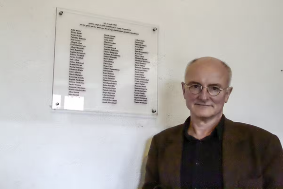 Hans-Joachim Lang devant la plaque commémorative comportant les noms des 86 victimes au camp de concentration de Natzweiler-Struthof, avril 2013.