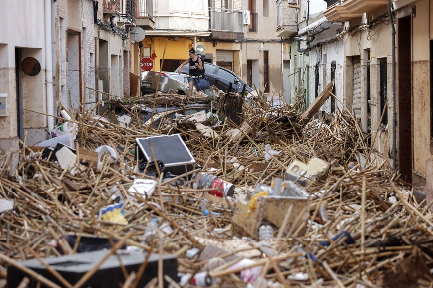 epa11692837 A resident walks over debris in the flood-hit municipality of Paiporta, in the province of Valencia, Spain, 30 October 2024. The intense rainfall impacting the eastern part of the country  ...