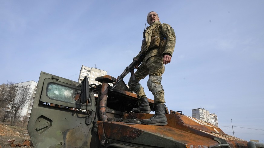 FILE - A Ukrainian soldier stands a top a destroyed Russian APC after recent battle in Kharkiv, Ukraine, on March 26, 2022. With Russia continuing to strike and encircle urban populations, from Cherni ...