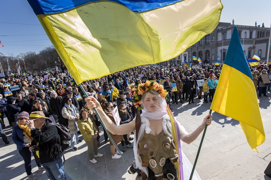 epa09804064 A protester wears a dress made from gas masks during a demonstration against the Russian invasion of Ukraine in Geneva, Switzerland, 05 March 2022. According to the United Nations (UN), at ...