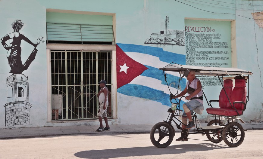 epa10065456 People pass in front of a mural in defense of the Cuban revolution in Havana, Cuba, 11 July 2022. Cuba remembers one year since the outbreak of 11J, the largest anti-government protests in ...