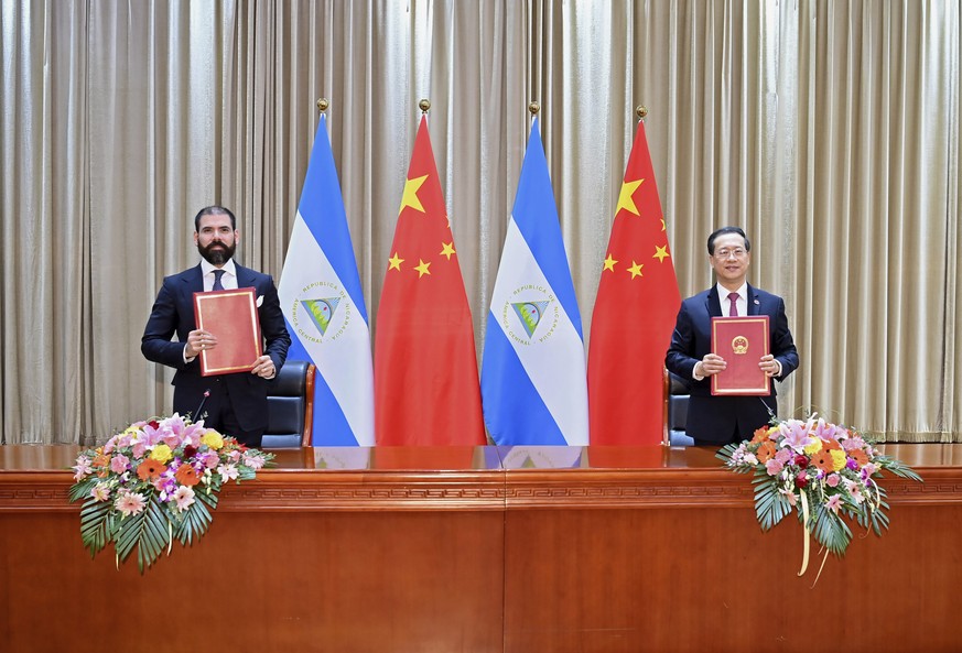 In this photo released by China's Xinhua News Agency, representatives from Nicaragua and China sign a joint communique on the resumption of diplomatic relations between the two countries in north ...