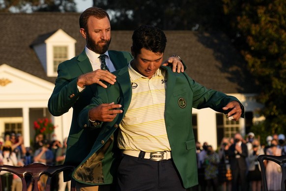 Dustin Johnson helps Hideki Matsuyama, of Japan, put on the champion&#039;s green jacket after winning the Masters golf tournament on Sunday, April 11, 2021, in Augusta, Ga. (AP Photo/David J. Phillip ...