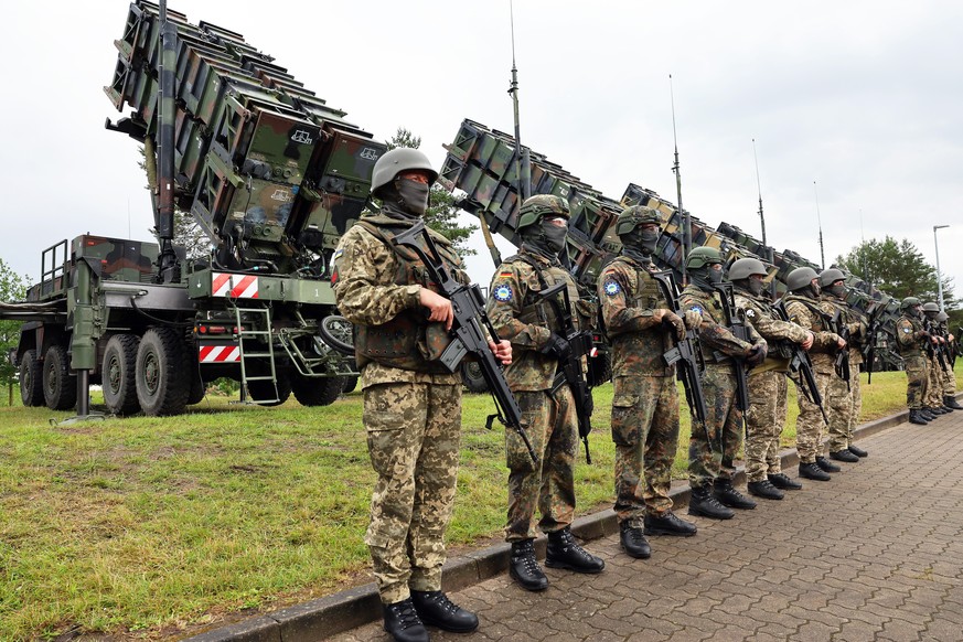 epa11404632 German and Ukrainian soldiers stand in front of 'Patriot' anti-aircraft missile systems during the visit of Ukrainian President Zelensky to a military training area in Germany, 1 ...