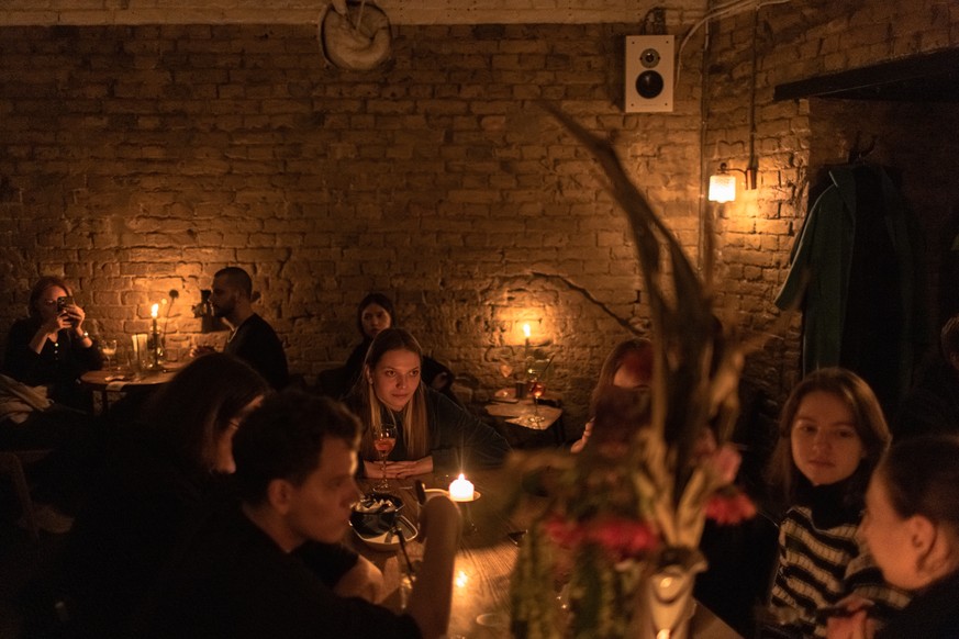 epa10292105 People sit in a restaurant illuminated with candles as blackouts continue in downtown Kyiv (Kiev), Ukraine, 06 November 2022 (issued 07 November 2022). Kyiv Mayor Vitali Klitschko asked re ...