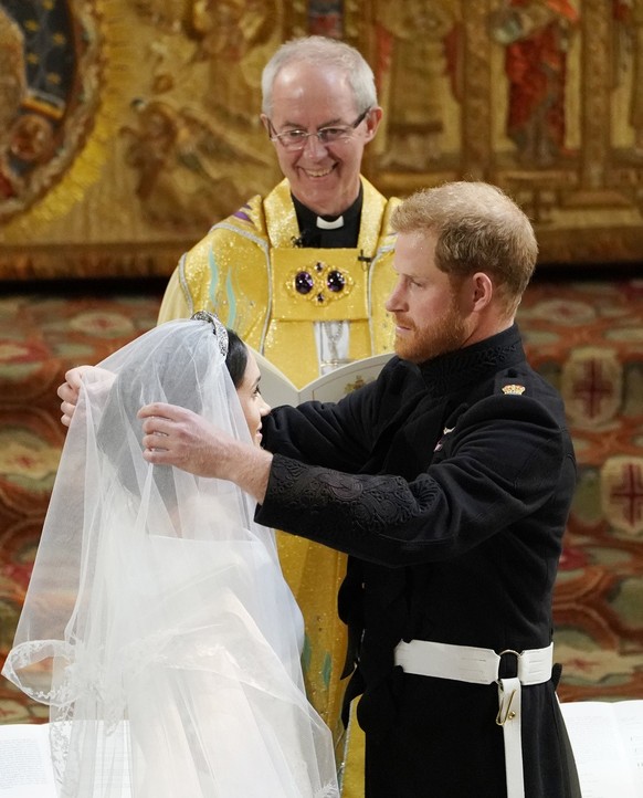 Britain&#039;s Prince Harry pulls back the veil of Meghan Markle watched by Archbishop of Canterbury Justin Welby during their wedding at St. George&#039;s Chapel in Windsor Castle in Windsor, near Lo ...