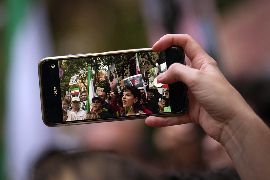 A woman records video on a mobile phone during a protest against the death of Iranian Mahsa Amini, outside the Iranian embassy in Bucharest, Romania, Saturday, Oct. 1, 2022. Amini, a 22-year-old woman ...