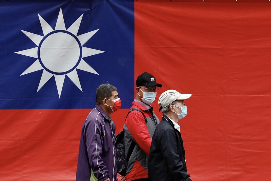 epaselect epa09573384 Taiwanese citizens walk next to the National flag in Taipei, Taiwan, 10 November 2021. A group of US senators and lawmakers arrived Taipei in the evening of 09 November on an und ...