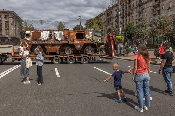 epa10130459 People pass Russian armoured military vehicle that was destroyed in fights with the Ukrainian army, placed on a truck trailer, on Khreshchatyk street, in downtown Kyiv, ahead of the ?Indep ...