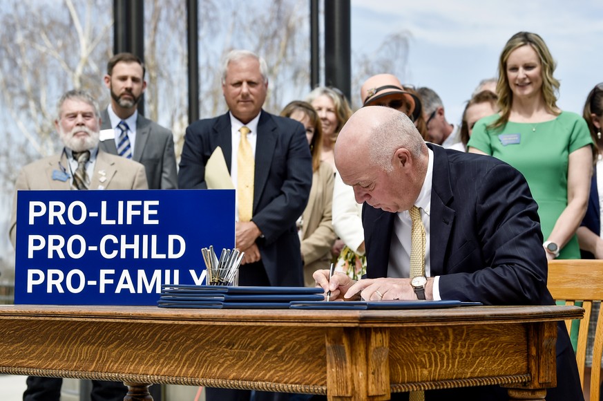 FILE - Gov. Greg Gianforte signs a suite of bills aimed at restricting access to abortion during a bill signing ceremony on the steps of the State Capitol, in Helena, Mont., on May 3, 2023. A judge on ...