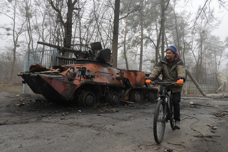 A local resident rides a bike past a destroyed military vehicle, in Irpin close to Kyiv, Ukraine, Friday, Apr. 1, 2022. Talks to stop the fighting in Ukraine resumed Friday, as another attempt to resc ...
