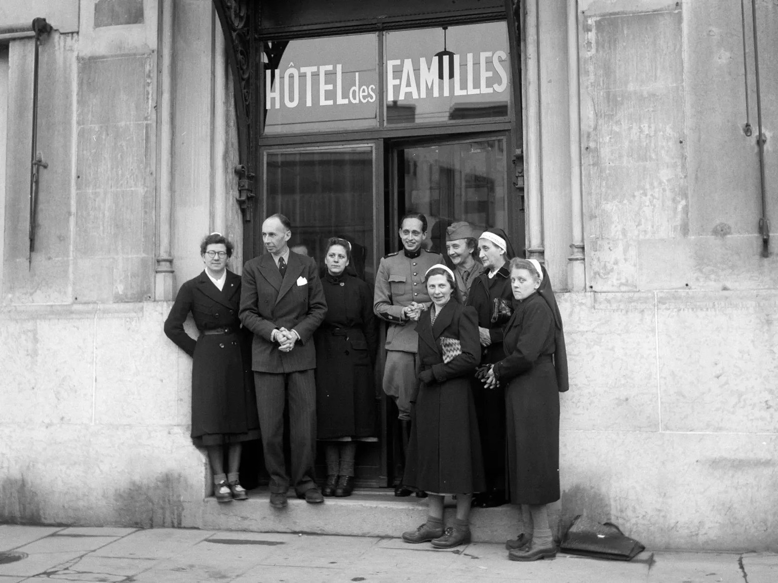 Des hommes et des femmes devant l’Hôtel des Familles à Genève, où étaient hébergés les enfants avant de poursuivre leur trajet.