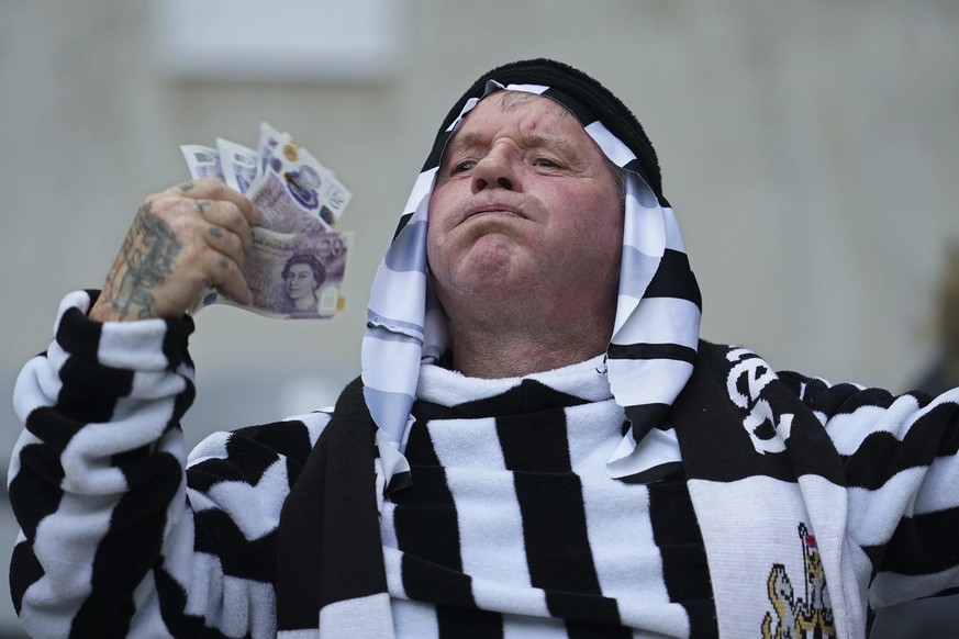 Un fan de Newcastle brandit une liasse de billets après le rachat des Saoudiens. 