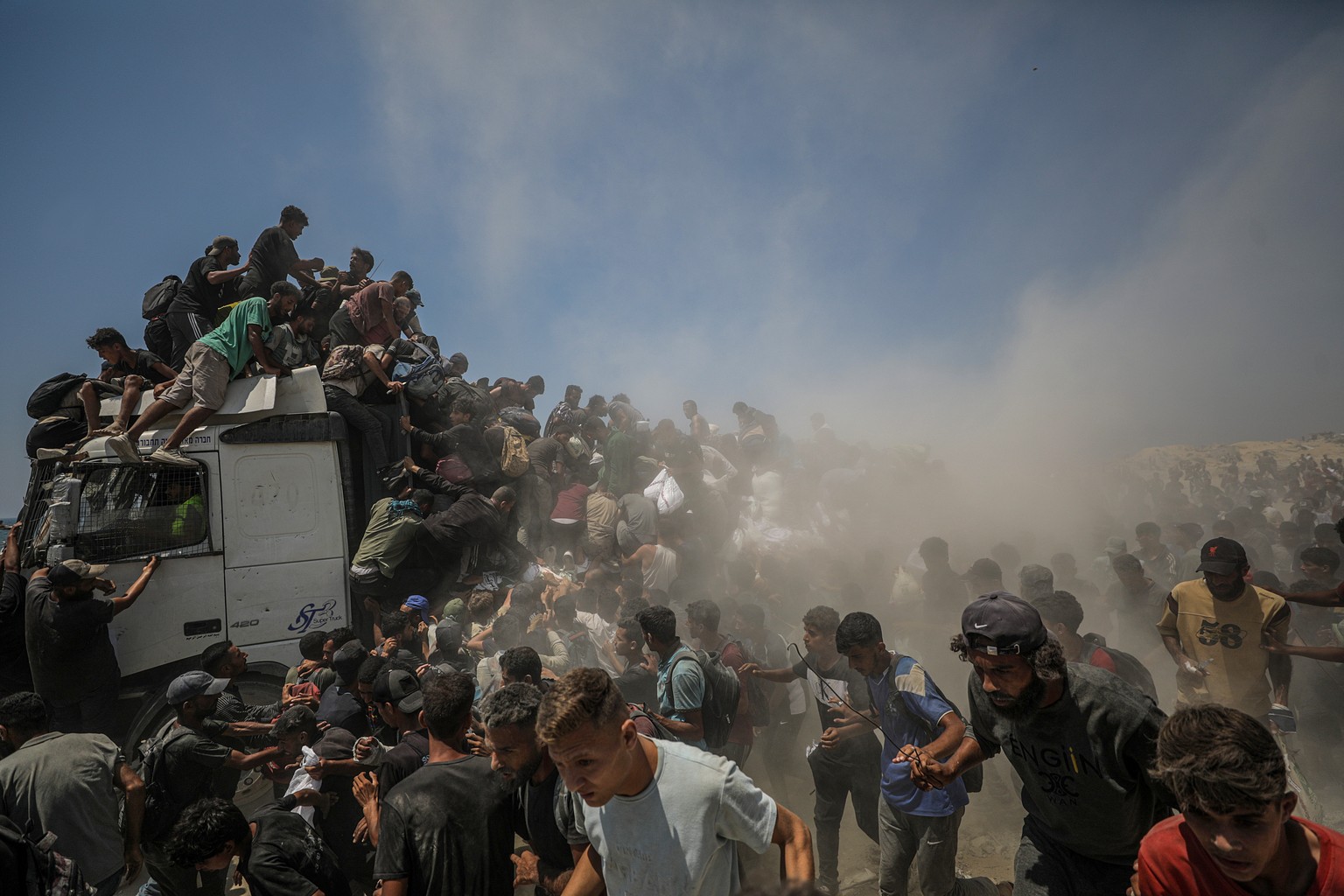epa12265737 Internally displaced Palestinians try to grab bags of flour from an aid truck near a food distribution point in Zikim, northern Gaza Strip, 27 July 2025. The Israeli army declared a &#039; ...