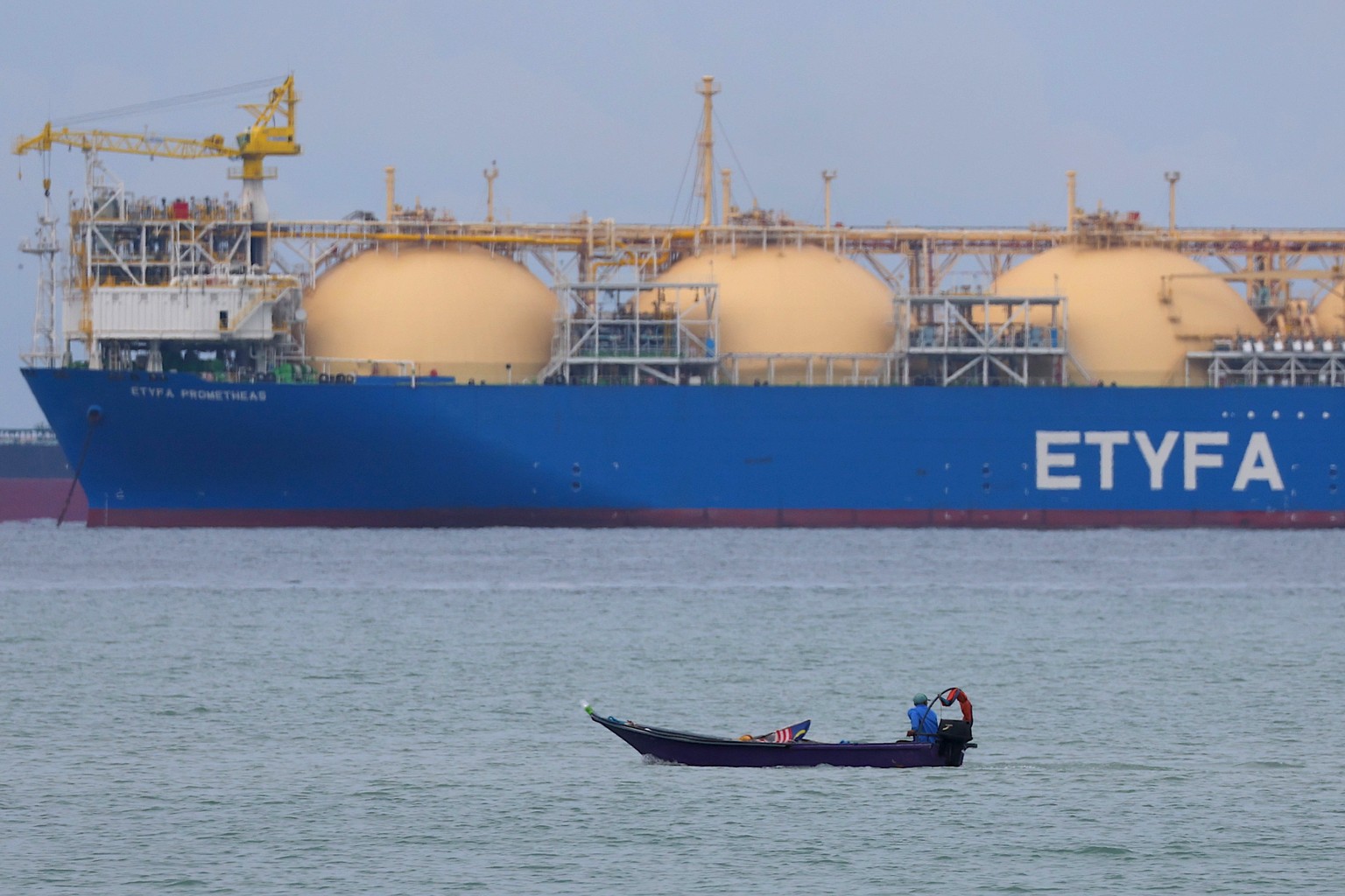 epa12048631 A fisherman passes by the liquefied natural gas (LNG) tanker ETYFA-Prometheas at the Malacca Strait in Malaysia, 23 April 2025. EPA/FAZRY ISMAIL