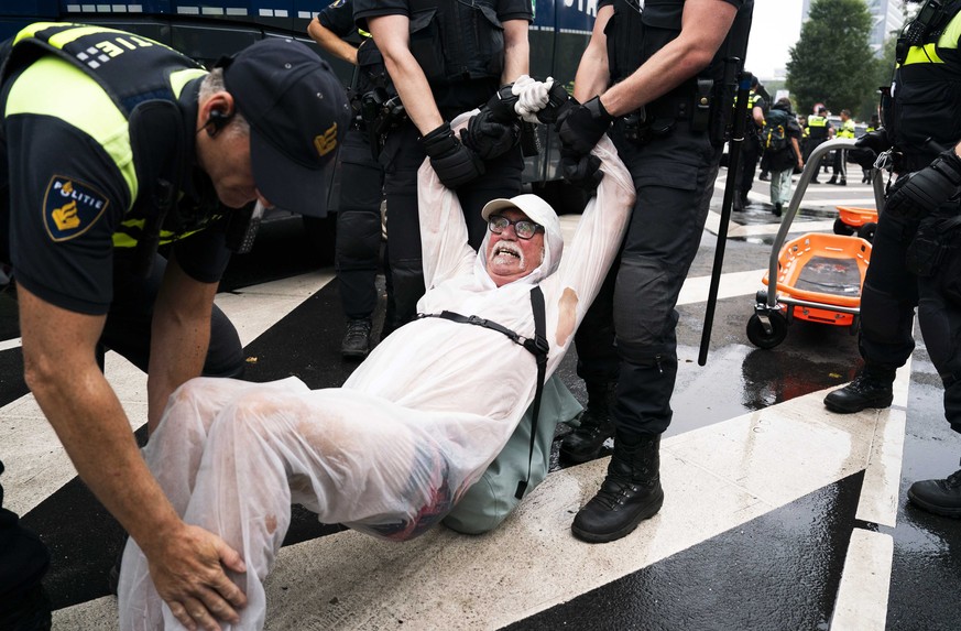 La police emporte un homme alors que des activistes bloquent la chaussée d'une autoroute à La Haye, lundi.