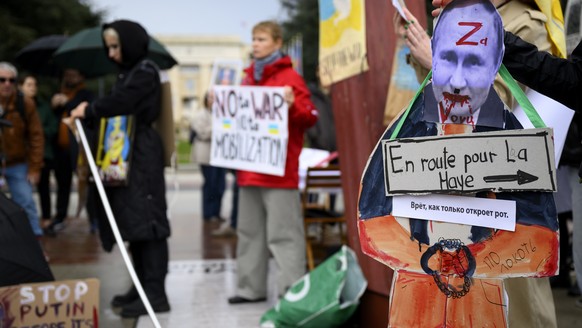 epa10205639 A Russian protestor carries a placard showing a picture of Russian president Vladimir Putin with the direction of The Hague, the seat of the UN International Court of Justice during a demo ...