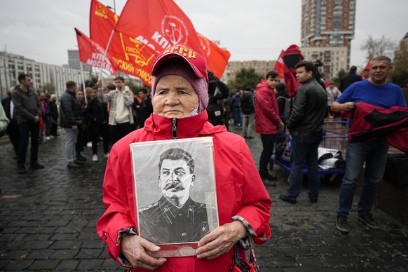 An elderly woman holds a portrait of aSoviet leader Josef Stalin as other people gather to march with flowers and portraits of those who were killed during the 1993 bloody clashes between government f ...