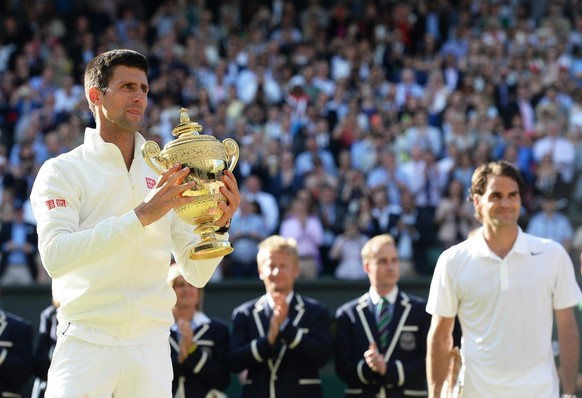 epa04302870 Novak Djokovic of Serbia holds the championship trophy following his win over Roger Federer of Switzerland in the men's singles final of the Wimbledon Championships at the All England ...