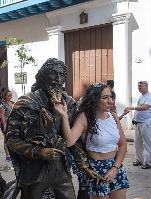 OLD HAVANA, HAVANA, CUBA - 2015/09/18: Cuba tourism: the Knight of Paris or El Caballero de Paris sculpture in Old Havana, Cuba. In the image, there is a living statue at the left and a woman having h ...