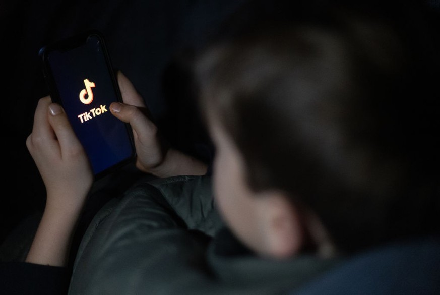 BATH, UNITED KINGDOM - MARCH 10: A 12-year-old boy looks at a smartphone screen displaying the TikTok logo on March 10, 2024 in Bath, England. Following the lead of the EU Commission and several US ad ...