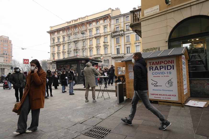 People line up at a mobile COVID testing site next to a pharmacy in Milan, Italy, Tuesday, Dec. 21, 2021. Nations across Europe have moved to reimpose tougher measures to stem a new wave of COVID-19 i ...