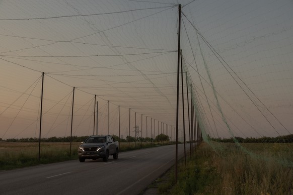 A military car drives on a road under anti-drone nets installed by Ukrainian servicemen at an undisclosed location in the eastern Donetsk region on July 8, 2025, amid the Russian invasion of Ukraine.  ...