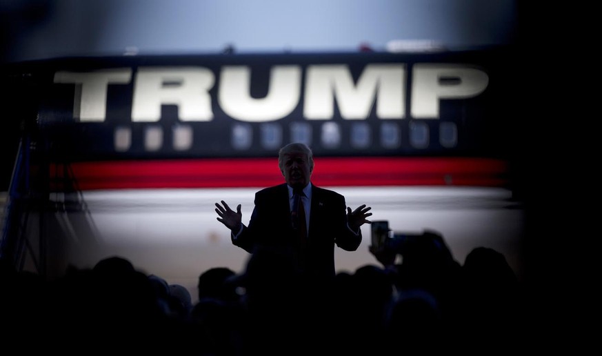 Republican presidential candidate Donald Trump is silhouetted against his plane as he speaks during a rally Saturday, Feb. 27, 2016, in Bentonville, Ark., as shot through the crowd. (KEYSTONE/AP Photo ...