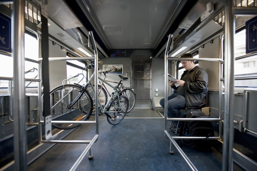 A man sits in a bicycle carriage of an InterCity train of the Swiss Federal Railways SBB from Berne to Biel, Switzerland, and reads a magazine, on November 27, 2009. (KEYSTONE/Gaetan Bally)
Ein Mann ...