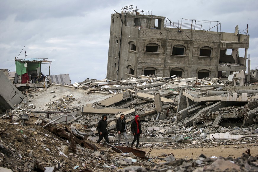 epa11880885 Palestinians walk between destroyed buildings in Al Remal neighbourhood amid a ceasefire between Israel and Hamas, in Gaza City, Gaza Strip, 07 February 2025. Israel and Hamas implemented  ...