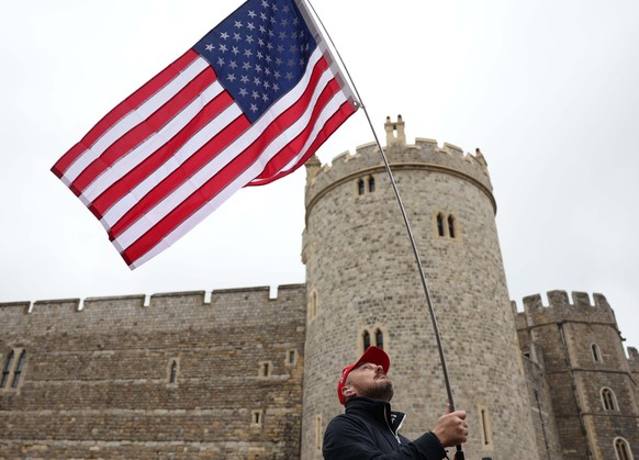 epa12384596 A man flies a US flag outside Windsor Castle in Windsor, Britain, 17 September 2025. Britain&#039;s King Charles III is hosting US President Trump during his official state visit to the UK ...