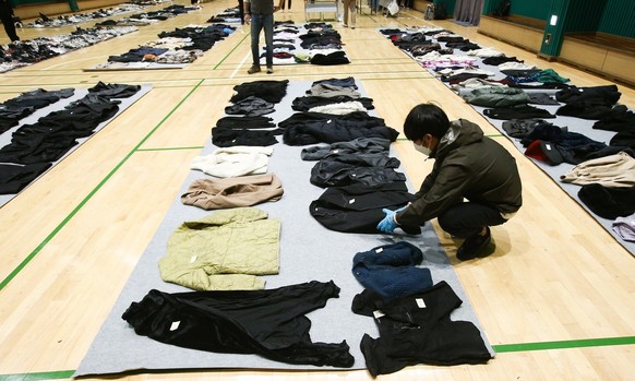 A police officer checks clothes collected from the scene of an stampede, at a multi-purpose gym in Seoul, South Korea, 01 November 2022. According to the National Fire Agency, at least 154 people were ...