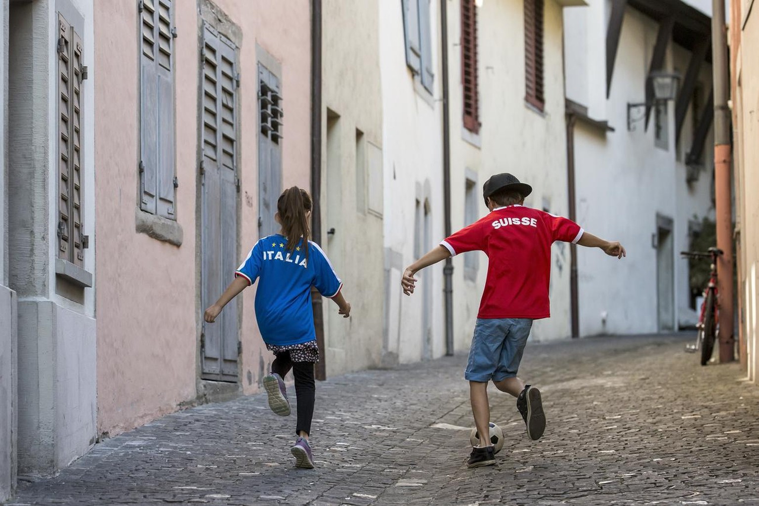 Das Fussballfieber ist nun auch in der Schweiz angekommen: Zwei Kinder mit einem italienischen und einem Schweizer Fussballtrikot spielen am Freitag, 3. Juni 2016, in den Gassen der Altstadt in Zug Fu ...