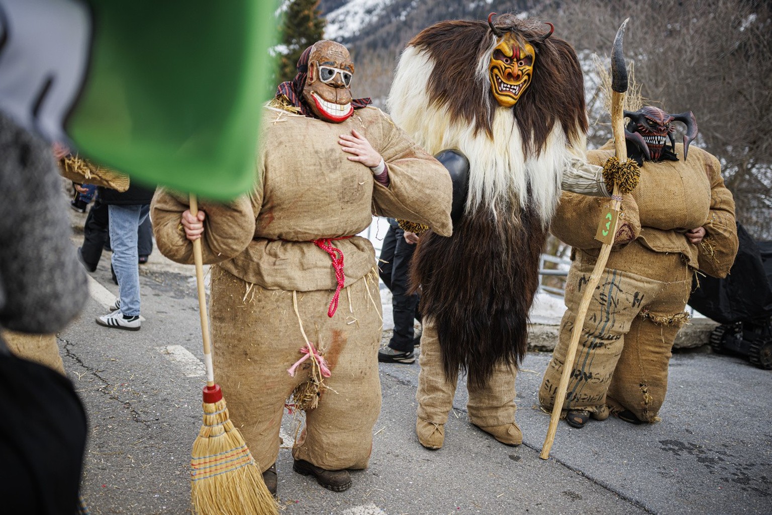 A "tschaeggaettae", center, and two "strawmen" parade on the streets of the alpine village of Wiler during carnival season in the Loetschental valley, southwestern Switzerland, Sat ...