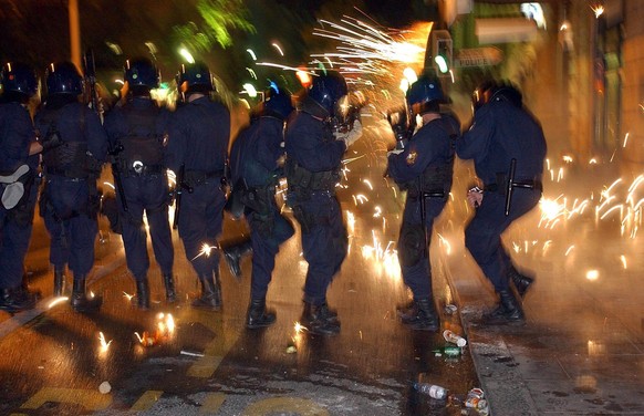 Swiss riot police take cover from exploding fireworks fired at them during riots in downtown Geneva, Monday June 2, 2003. Hundreds of anti-G-8-demonstrators were locked up on Geneva&#039;s main bridge ...
