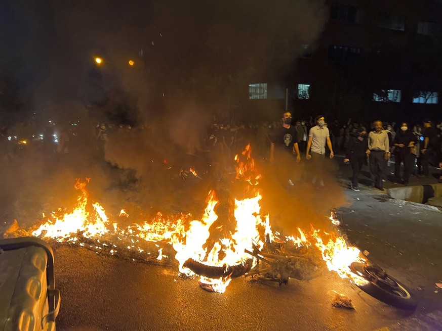 In this Monday, Sept. 19, 2022, photo taken by an individual not employed by the Associated Press and obtained by the AP outside Iran, a police motorcycle burns during a protest over the death of a yo ...