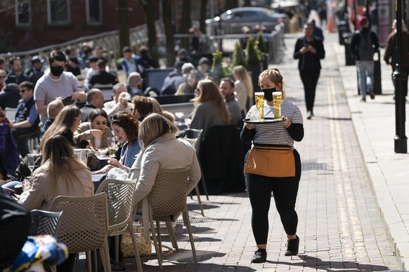 Customers sit outside bars and restaurants on Canal Street in the Gay village in Manchester Monday, April 12, 2021, as restaurants, bars and pubs can open and serve people who can be seated outside. M ...