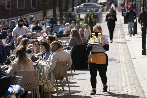 Customers sit outside bars and restaurants on Canal Street in the Gay village in Manchester Monday, April 12, 2021, as restaurants, bars and pubs can open and serve people who can be seated outside. M ...