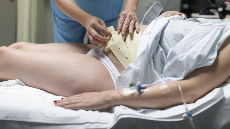 A midwife places a cardiotocograph onto an expectant mother&#039;s belly to monitor the fetus and the contractions, pictured at the maternity unit of the Triemli Hospital in Zurich, Switzerland, on Se ...