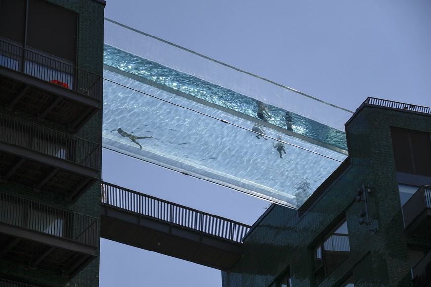 People swim in the Sky Pool, a transparent swimming pool bridge across two exclusive residential blocks standing next to the US Embassy in Nine Elms, in London, Tuesday, June 1, 2021. Britain sees tem ...