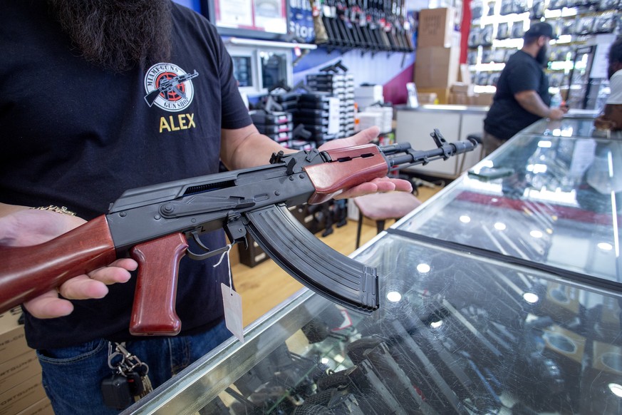 epa10028672 A worker at the Miami Guns Store and Range shows an AK-47 gun, in Hialeah, Florida, USA, 22 June 2022. On 21 June a bipartisan group of US senators released the Bipartisan Safer Communitie ...