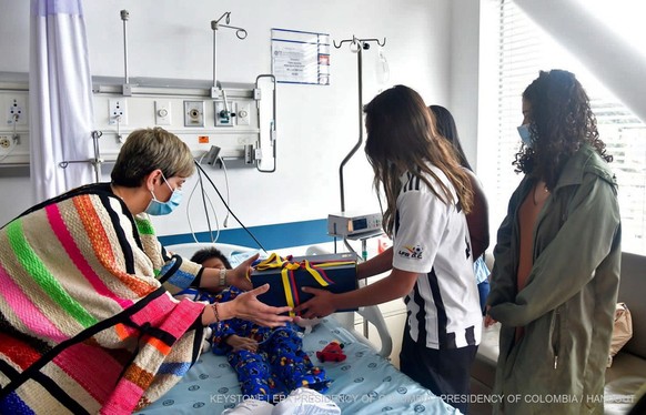 epa10683971 A handout photo made available by the Presidency of Colombia shows Colombian First Lady Veronica Alcocer (L) during her visit to the four siblings who were found alive after surviving a pl ...