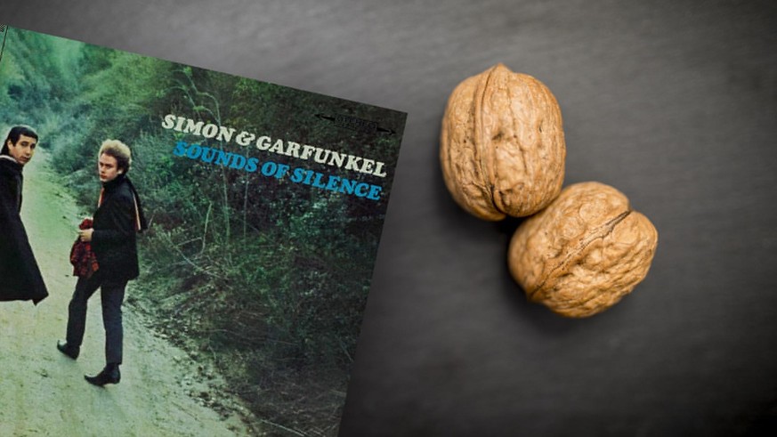 Close up of two walnuts on a black slate background.