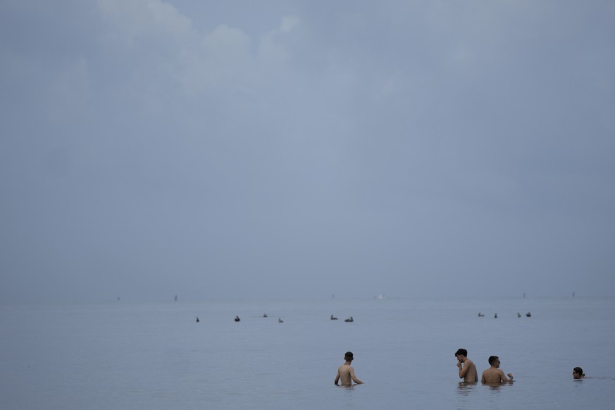 FILE - People swim in the ocean off of Crandon Park, July 28, 2023, in Key Biscayne, Fla. At about summer&#039;s halfway point, the record-breaking heat and weather extremes are both unprecedented and ...