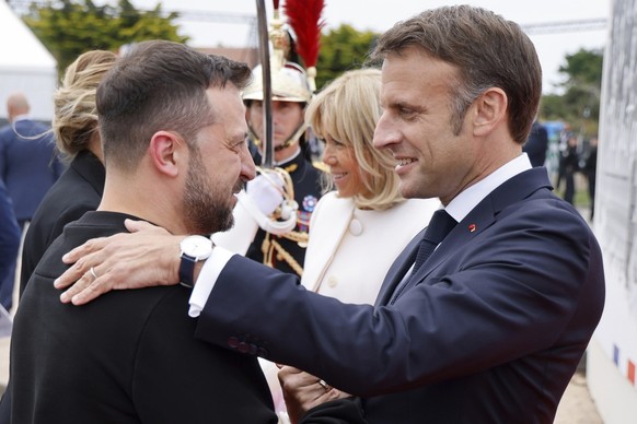 Ukrainian President Volodymyr Zelenskyy, left is greeted by French President Emmanuel Macron, at the international ceremony at Omaha Beach, near Saint-Laurent-sur-Mer. Thursday, June 6, 2024. Normandy ...