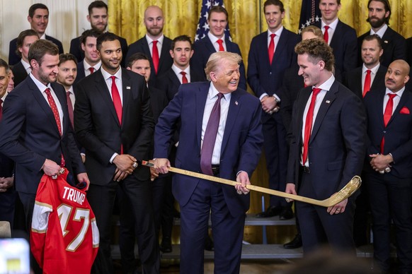 January 15, 2026, Washington, Dc, United States of America: U.S. President Donald Trump, center, holds a golden hockey stick, as he jokes with forward Matthew Tkachuk, right, during an event celebrati ...